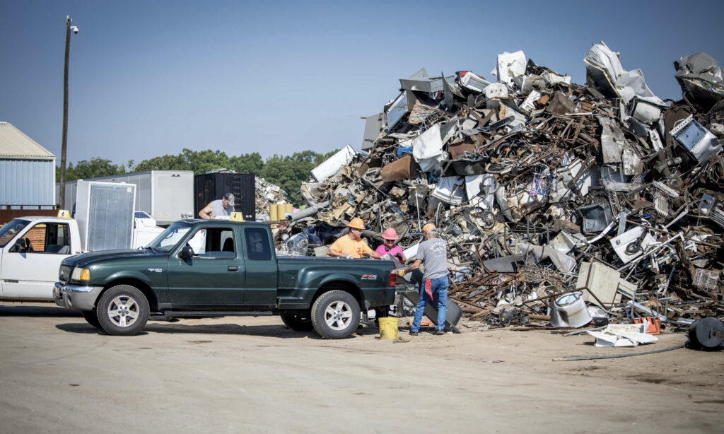 workers removing scrap car parts from the back of a Ford Ranger
